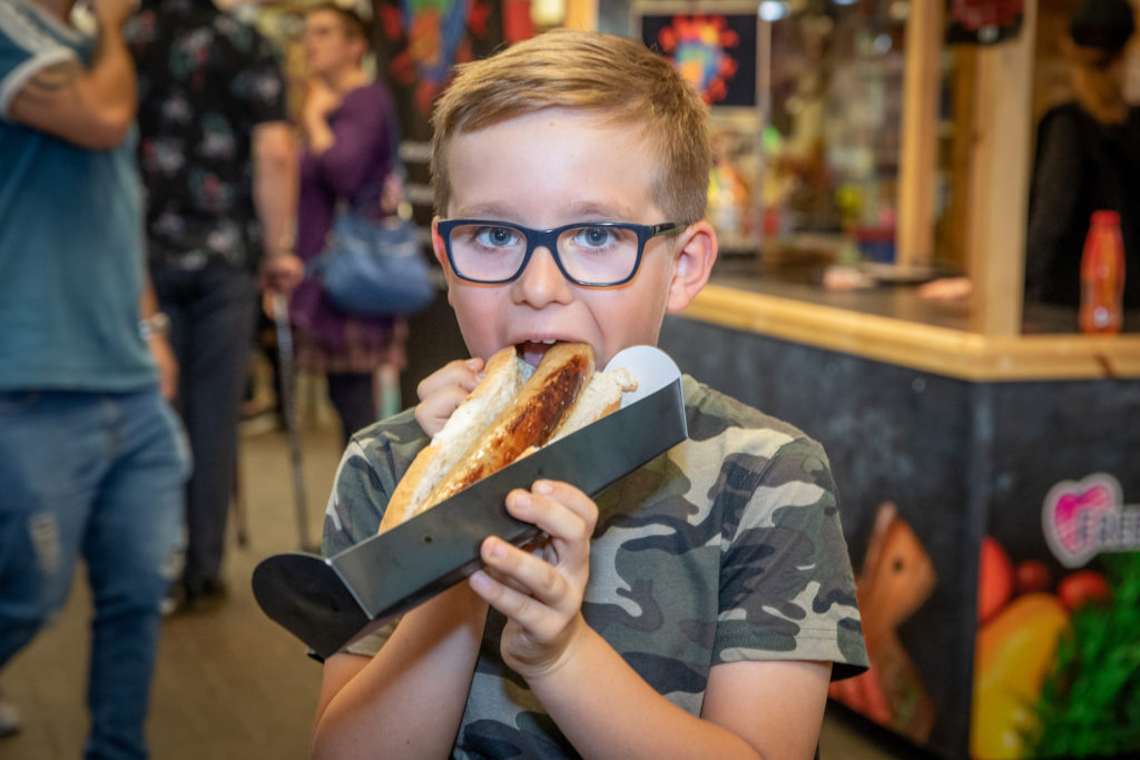 Young boy in a camouflage t shirt eating a hot-dog